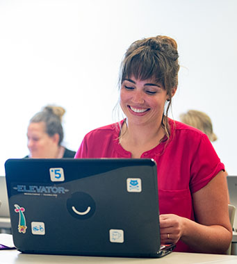 Smiling female computer science student with laptop.