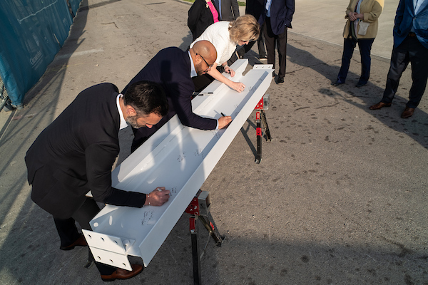 Tyler Kocher with OhioHealth, and Tywan Banks and Rebecca Butler with Columbus State, sign the beam.