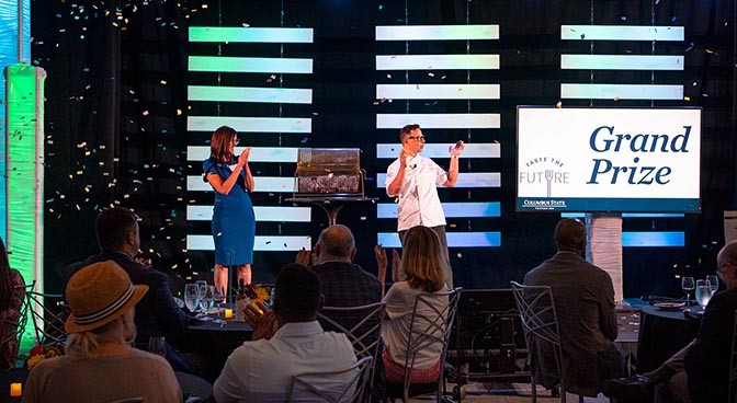 Above, Katy Trombitas, vice president of Advancement, and Josh Wickham, senior director of the School of Hospitality Management and Culinary Arts, react after announcing the winner of the Grand Prize drawing at the end of Taste the Future in Mitchell Hall on August 10. 