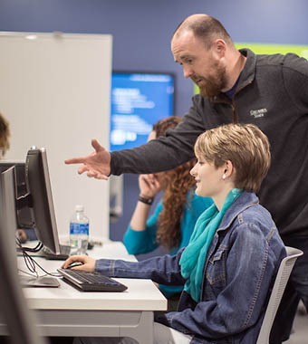 Professor instructing student on computer.