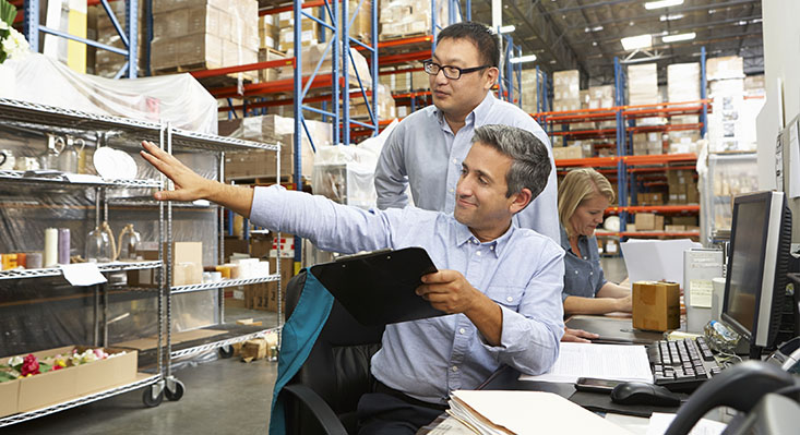 Men sitting at computers in warehouse