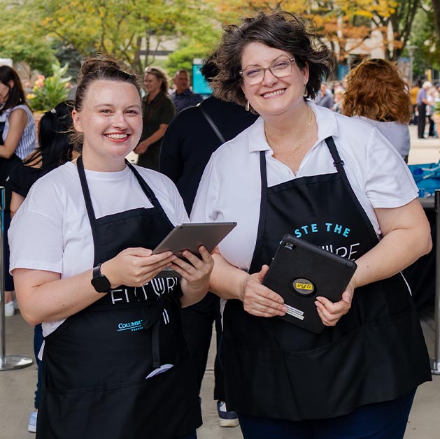 Two female employee volunteers at college event