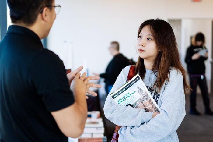 students talk to a university representative at a transfer fair