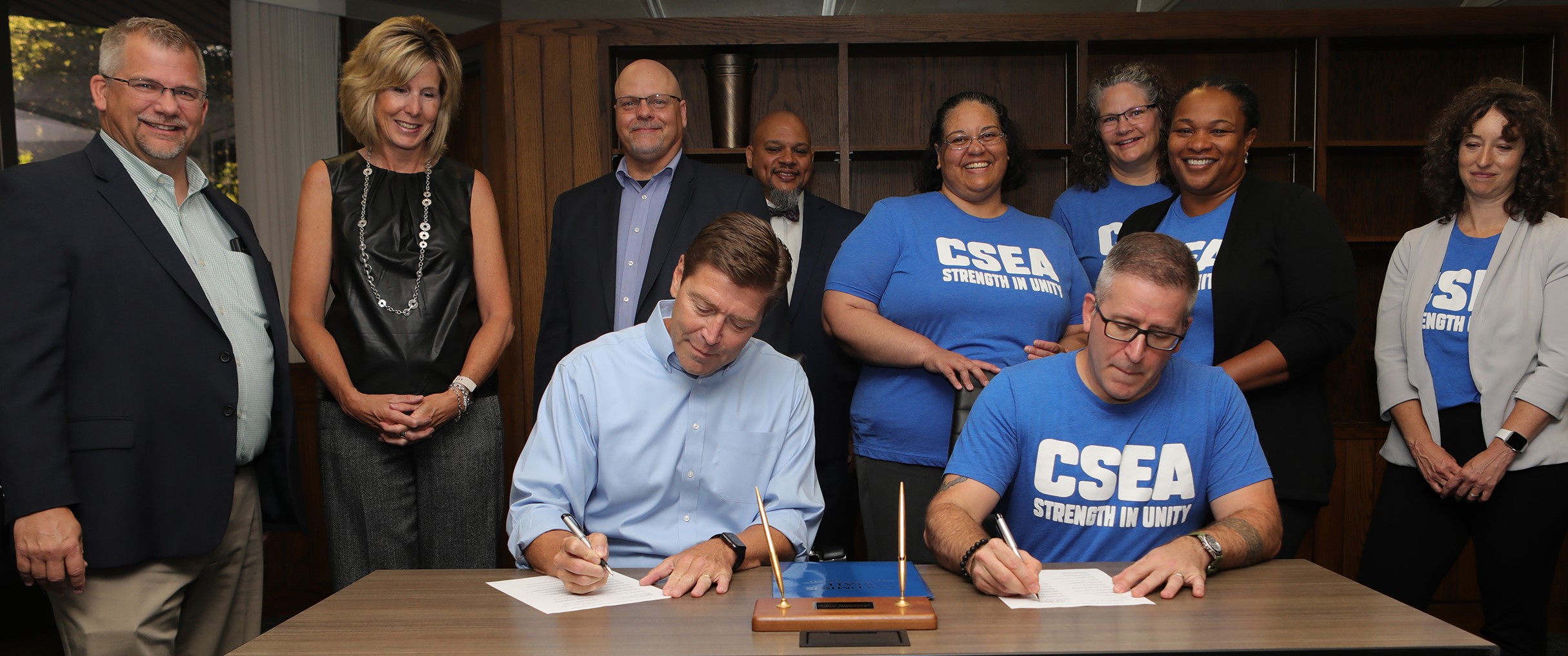 President Harrison, sitting on the left, with Adam Keller, Columbus State professor and faculty union president, during a ceremonial signing of the new CSEA contract in Franklin Hall on July 13. Standing, left to right, Rick Hatcher, vice president of Administration; Rebecca Butler, executive vice president; Marty Maliwesky, senior vice president and chief academic officer; Dale Gresson, Justice/Safety/Legal Studies executive administrator; Rachel Brooks-Pannell, English associate professor; Leslie Smith, mathematics professor; Antoinette Perkins, Sport Exercise Studies & Hospitality Programs professor; and Kristen Oganowski, Humanities instructor.