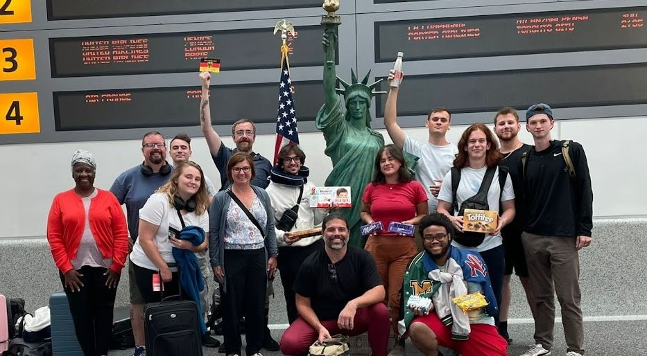 arriving in New York on Aug. 23 after a long trip home: faculty Patricia Opong (far left), Jeremy Banta (second from left), Adele Wright (front row standing, left of flag), and Andy Woodmansee (kneeling, left). Each assisted with hosting on the Columbus Campus in 2023 and the travel plans to Germany this year.