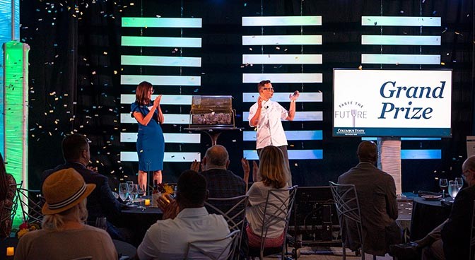 Katy Trombitas, vice president of Advancement, and Josh Wickham, senior director of the School of Hospitality Management and Culinary Arts, react after announcing the winner of the Grand Prize drawing at the end of Taste the Future in Mitchell Hall on August 10. 