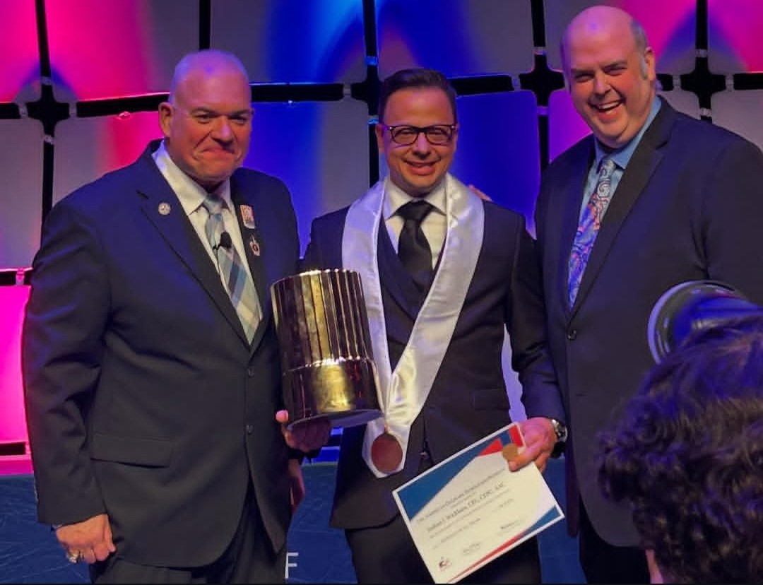 Chef Josh Wickham, in the middle, wins the ACF Chef Educator of the Year Award on July 31 during an awards ceremony in Las Vegas. On the left is Chef Rene Marquis, ACF national president. On the right is Chef Casey Schiller, lead judge for the competition.
