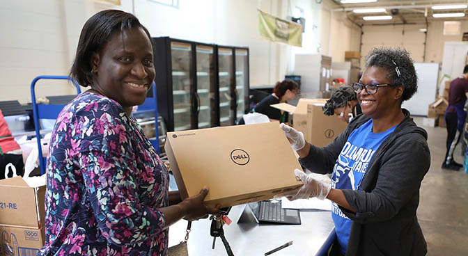 
Bola Ayodele (on the left) is a student receiving a Chromebook from Lisa Phillips, Student Financial Stability administrator.

