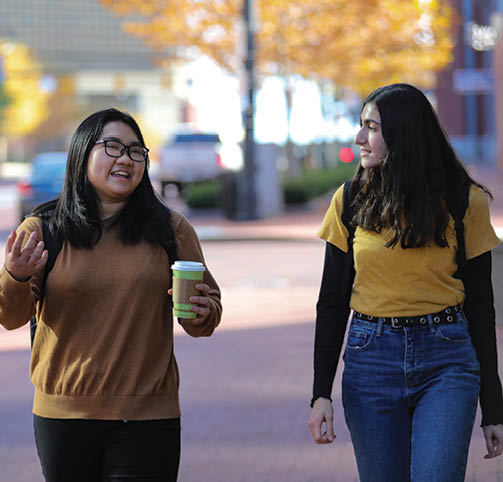 2 international students studying at coffee shop on laptops Thy is a Nursing major, graduation date of 2022. Heba is Political Science major, SP 2022 graduation.