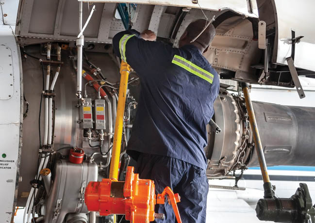 Three African mechanics repairing a plane engine in the hangar